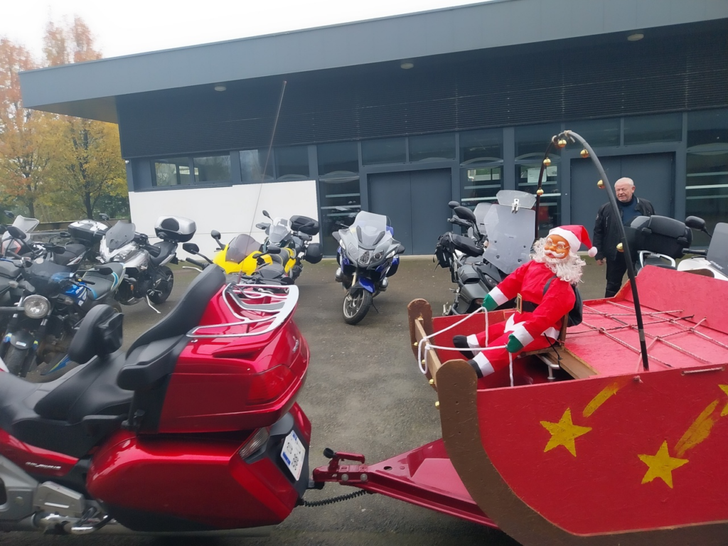 Plusieurs moto garées, avec devant une moto tirant une remorque transformée en traineau du pêre noël