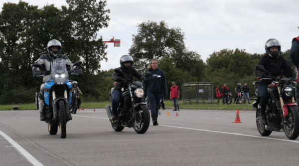 3 motards et une piétonne en train d'avancer sur un plateau