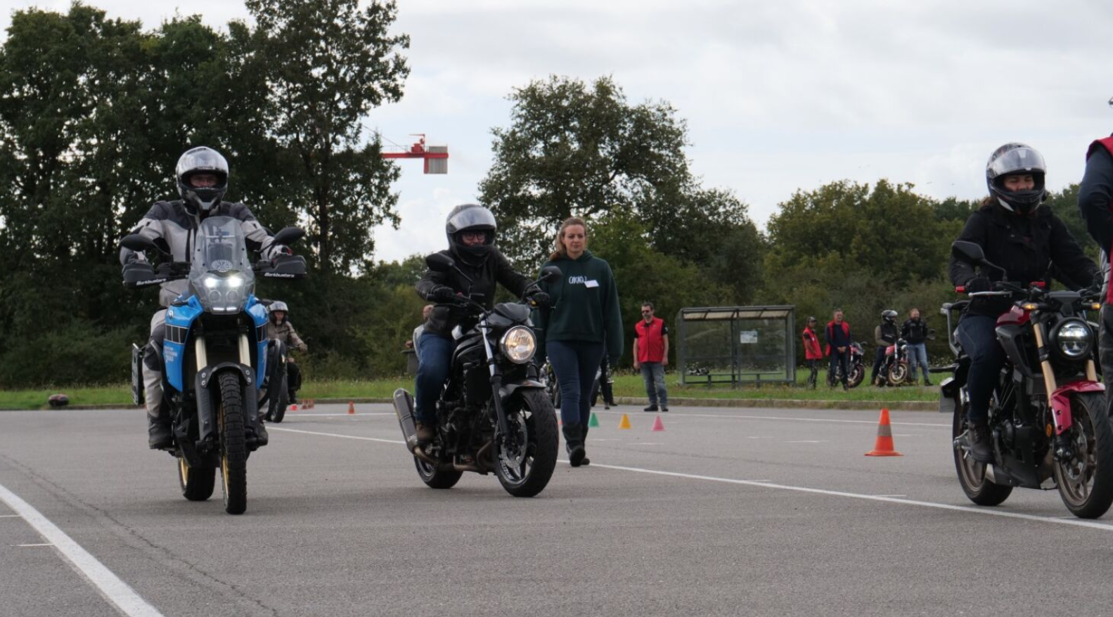 3 motards et une piétonne en train d'avancer sur un plateau
