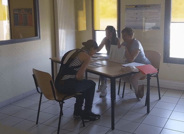 3 femmes dans une petite salle, la première regardant une photo